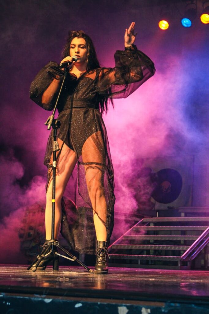 Energetic female singer in black outfit captivating the audience during a live concert.